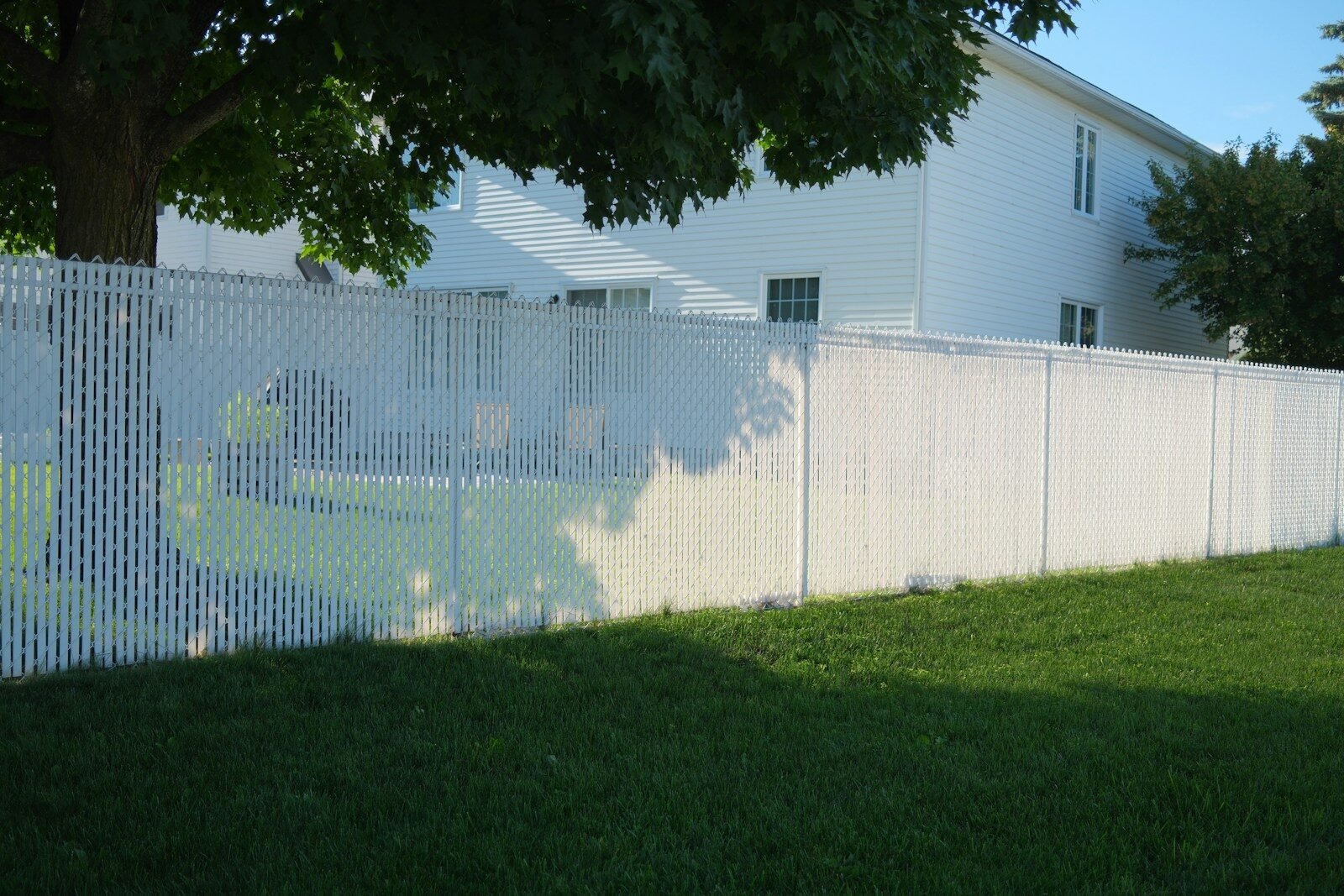 White vinyl privacy fence beside a lawn